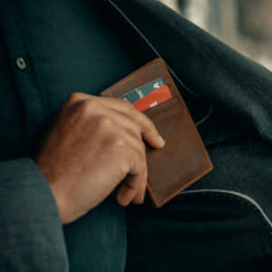 A hand putting a wallet in the inside pocket of a jacket